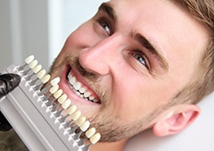 Man's smile compared with tooth color chart