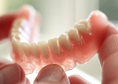 Hand holding a full denture